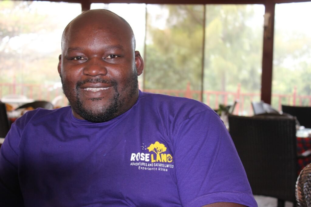 Patrick Odoyo smiling in a purple Roselands Adventures and Safaris shirt