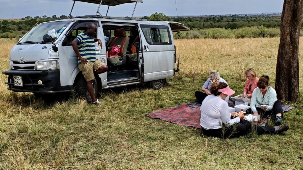 Group resting beside a safari vehicle during a journey through open grassland